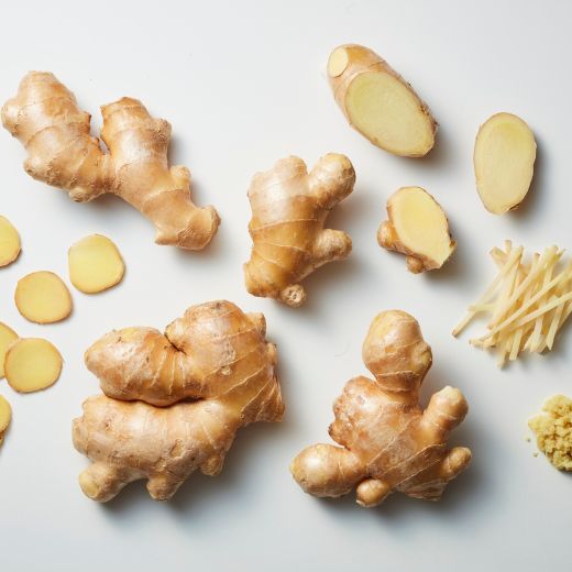Whole ginger roots, sliced rounds, julienned pieces, and minced ginger arranged neatly on a clean white background.